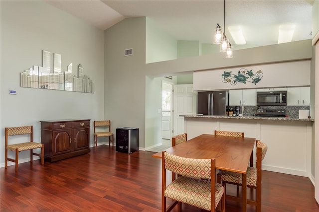 dining room with dark hardwood / wood-style flooring and high vaulted ceiling