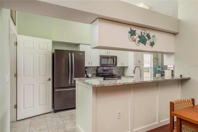 kitchen featuring white cabinets, appliances with stainless steel finishes, tasteful backsplash, light stone counters, and kitchen peninsula