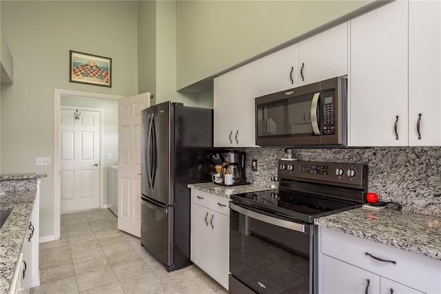 kitchen featuring light tile patterned floors, light stone countertops, white cabinetry, and appliances with stainless steel finishes