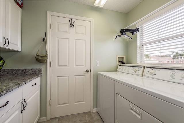 laundry room with cabinets, independent washer and dryer, a textured ceiling, and light tile patterned flooring