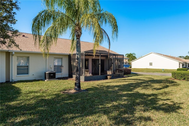 rear view of property featuring a lanai, a yard, and central AC