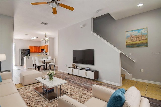 living room with light tile patterned floors and ceiling fan with notable chandelier