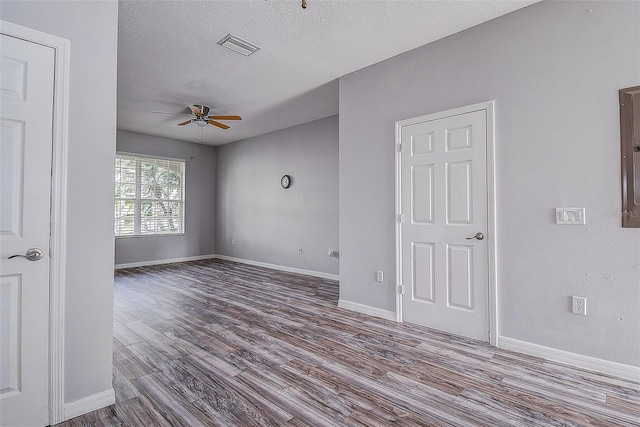 empty room with ceiling fan, wood-type flooring, and a textured ceiling