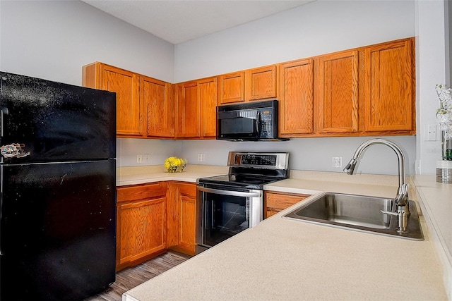 kitchen with black appliances, wood-type flooring, and sink