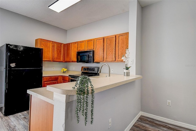 kitchen featuring kitchen peninsula, sink, black appliances, and hardwood / wood-style flooring