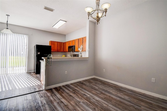 kitchen with kitchen peninsula, dark hardwood / wood-style flooring, black appliances, a notable chandelier, and hanging light fixtures