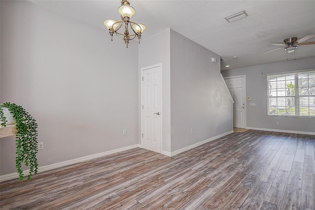 spare room with ceiling fan with notable chandelier, wood-type flooring, and a textured ceiling