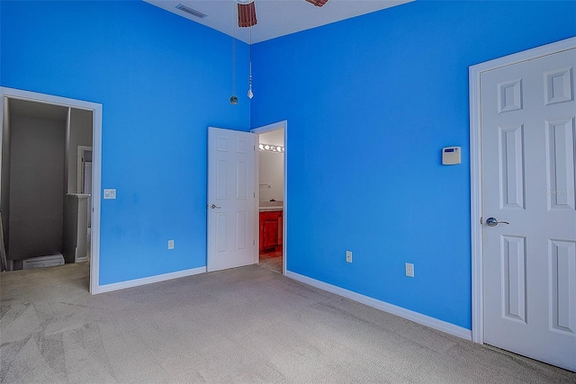 unfurnished bedroom featuring ceiling fan, carpet floors, and a towering ceiling