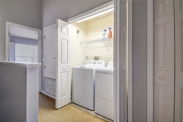 laundry area with washing machine and dryer and light carpet