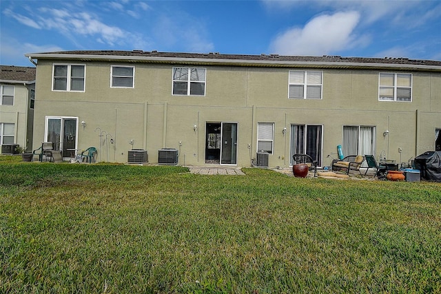 rear view of property with central air condition unit and a lawn