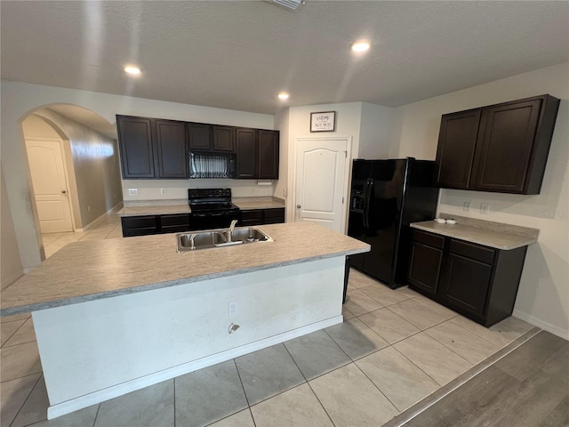 kitchen featuring sink, an island with sink, black appliances, and light tile patterned floors