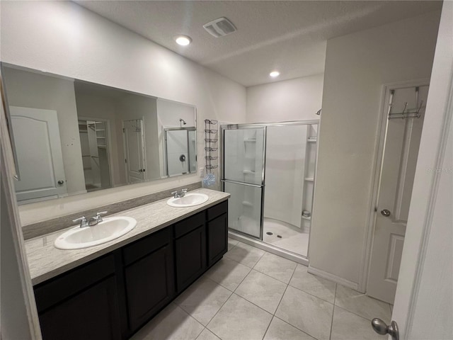 bathroom featuring tile patterned flooring, vanity, a shower with shower door, and a textured ceiling