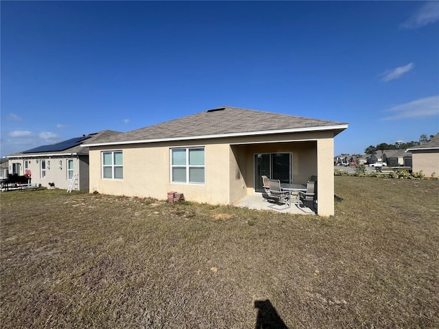 back of house featuring a lawn, a patio, and solar panels