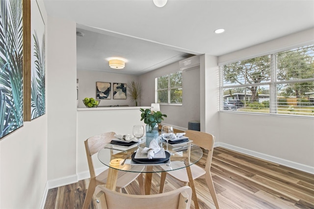 dining area featuring plenty of natural light, a wall mounted AC, and wood-type flooring