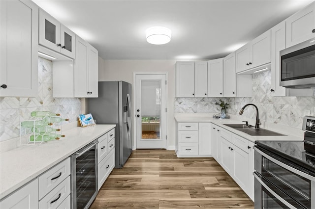 kitchen featuring stainless steel appliances, beverage cooler, light wood-type flooring, and white cabinets