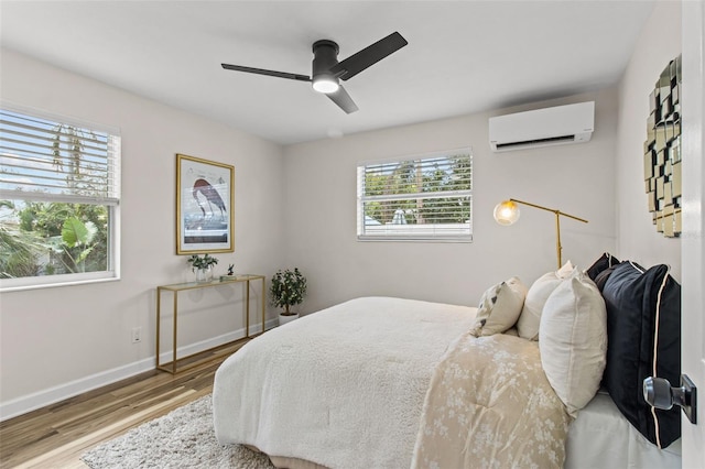 bedroom featuring ceiling fan, hardwood / wood-style floors, and a wall unit AC