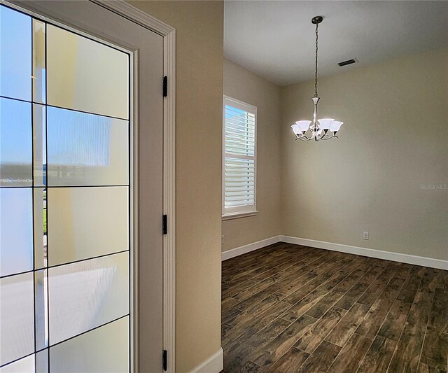 unfurnished dining area featuring dark hardwood / wood-style flooring and a notable chandelier