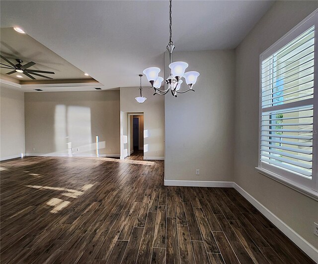 spare room featuring dark hardwood / wood-style flooring, a raised ceiling, and ceiling fan with notable chandelier