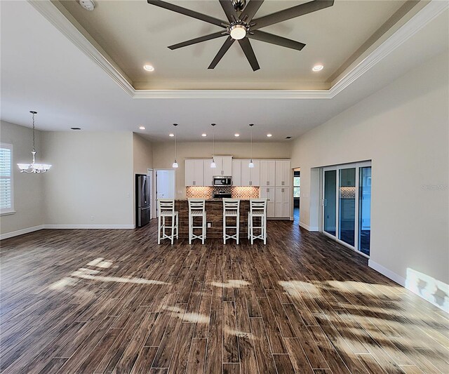 interior space with stainless steel appliances, decorative light fixtures, a breakfast bar area, white cabinetry, and a large island