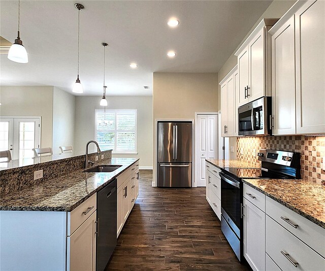 kitchen with backsplash, pendant lighting, a kitchen island with sink, white cabinets, and appliances with stainless steel finishes