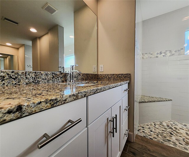 bathroom with a tile shower, hardwood / wood-style floors, and vanity