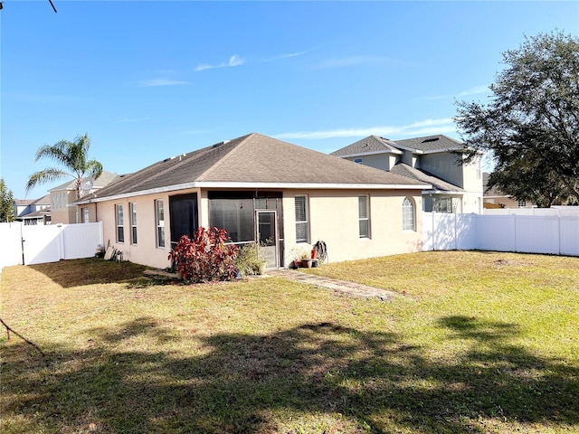 rear view of house featuring a sunroom and a yard