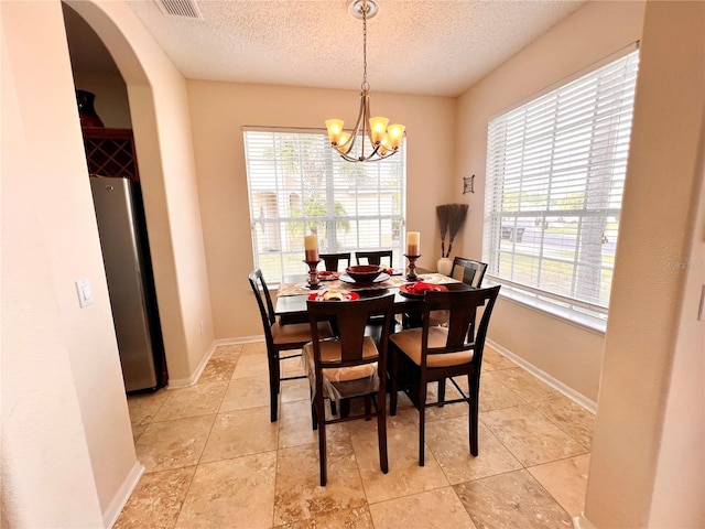 tiled dining space with a textured ceiling and a notable chandelier