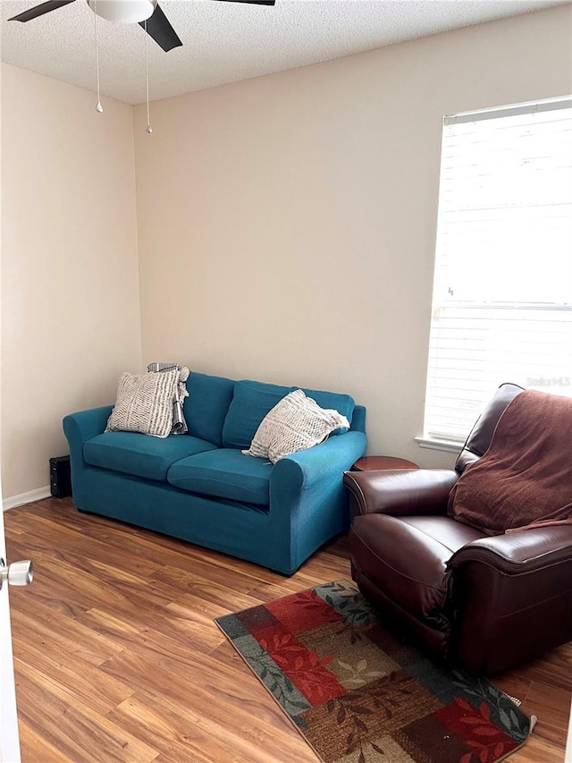 living room with ceiling fan, wood-type flooring, and a textured ceiling