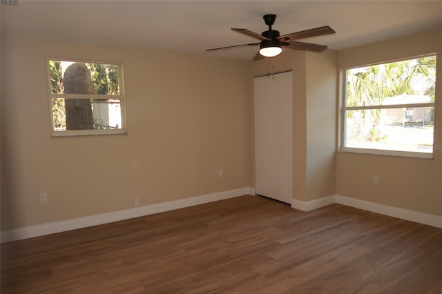 unfurnished bedroom featuring ceiling fan, wood-type flooring, and multiple windows