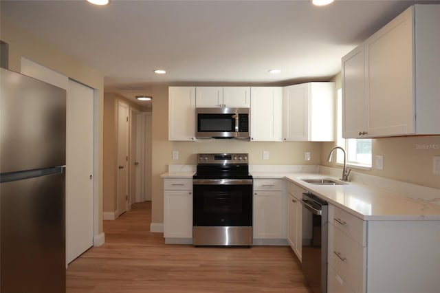 kitchen with white cabinets, appliances with stainless steel finishes, light wood-type flooring, and sink