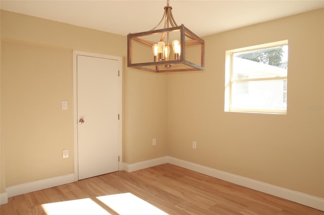 unfurnished room featuring a chandelier and light wood-type flooring