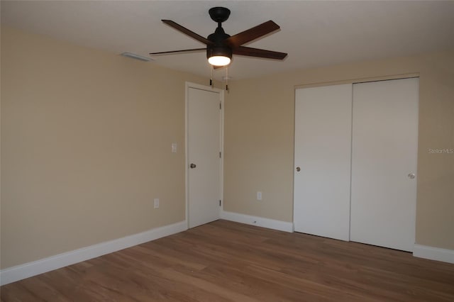 unfurnished bedroom featuring ceiling fan, a closet, and wood-type flooring