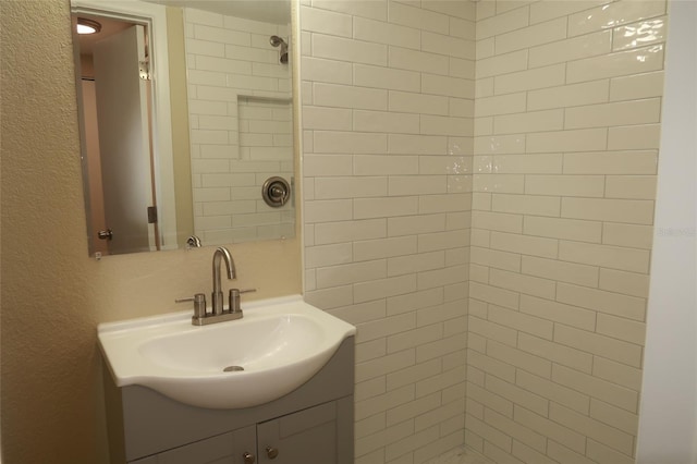 bathroom with a tile shower and vanity