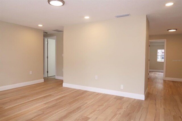 empty room featuring light wood-style floors, baseboards, recessed lighting, and visible vents