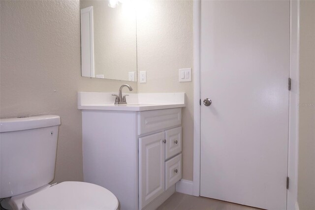 half bath featuring vanity and toilet