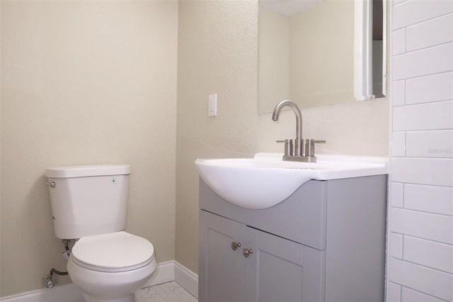 bathroom with baseboards, vanity, and toilet