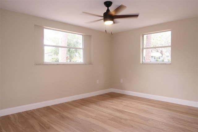 spare room with baseboards, ceiling fan, and light wood finished floors