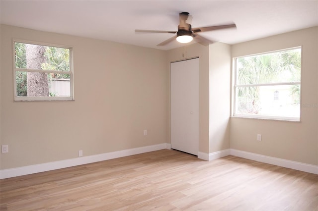 spare room with baseboards, ceiling fan, and light wood-style flooring