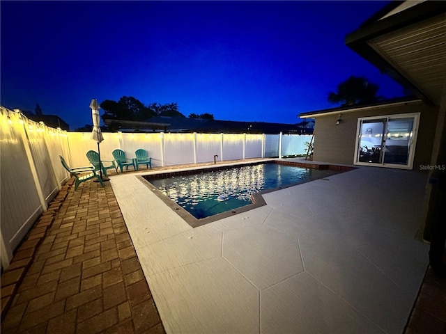 pool at night with a patio area