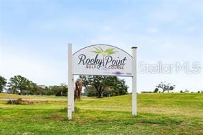 community / neighborhood sign with a rural view and a lawn