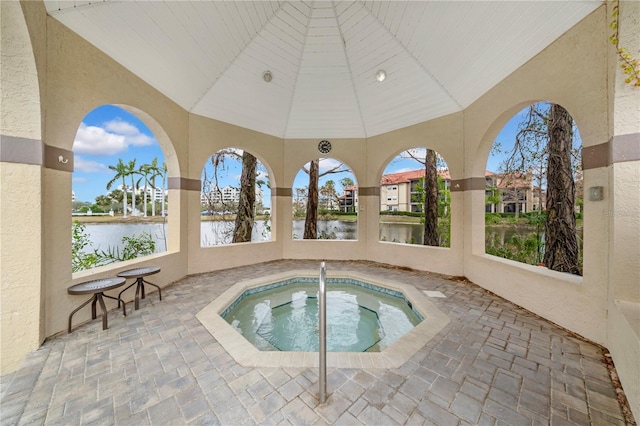 view of pool featuring a water view and a hot tub