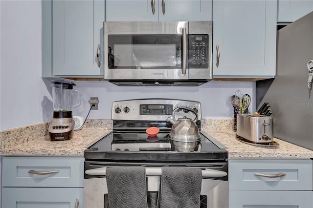 kitchen featuring appliances with stainless steel finishes and light stone counters