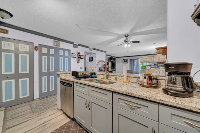 kitchen featuring sink, stainless steel dishwasher, gray cabinets, a textured ceiling, and light stone counters