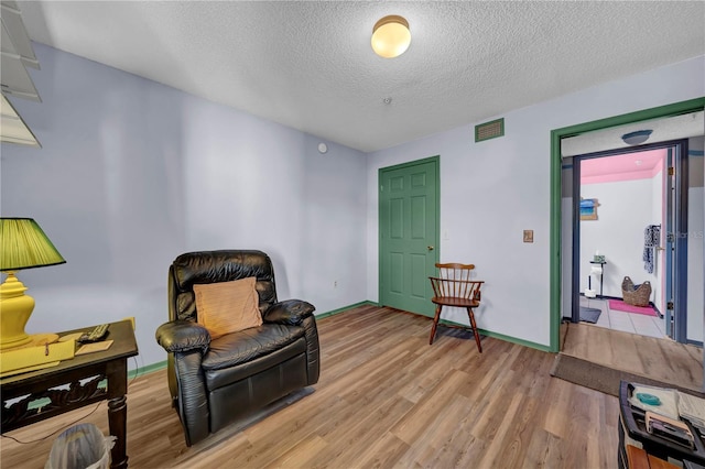 living area with a textured ceiling and light hardwood / wood-style flooring