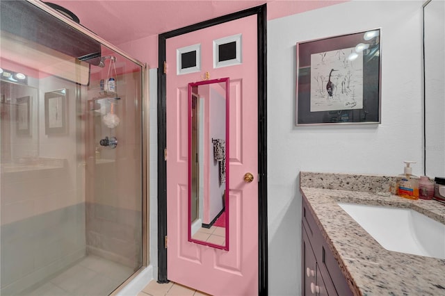 bathroom with tile patterned flooring, vanity, and walk in shower