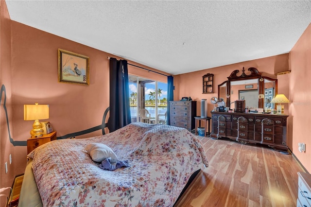 bedroom featuring light hardwood / wood-style floors, a textured ceiling, and access to outside