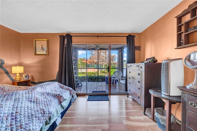 bedroom featuring light wood-type flooring, a textured ceiling, and access to outside