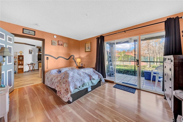 bedroom featuring a textured ceiling, light wood-type flooring, and access to outside