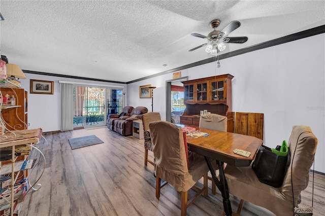 dining room with a textured ceiling, ceiling fan, light wood-type flooring, and crown molding