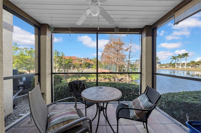 sunroom / solarium with ceiling fan and a water view